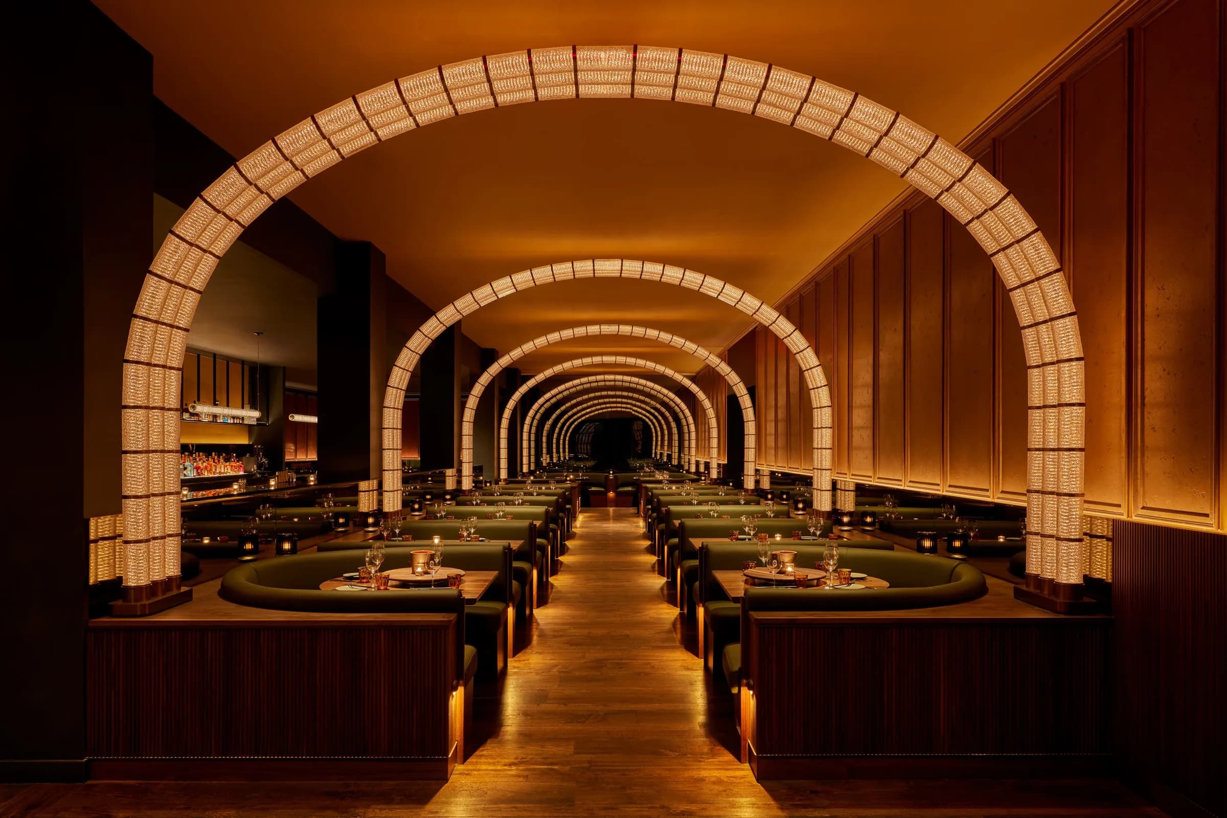 A candlelit dining room beneath a colonnade of glowing arches